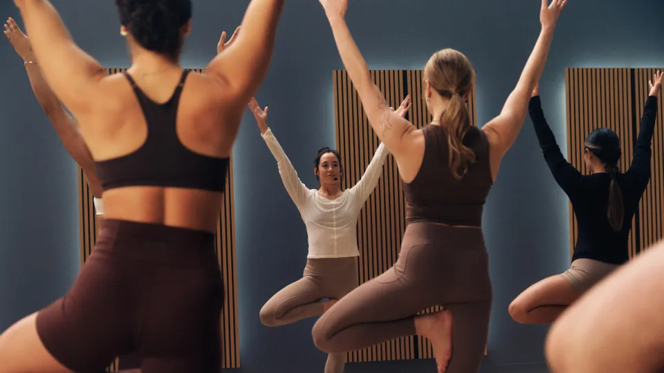 A group of people in a studio practicing tree pose