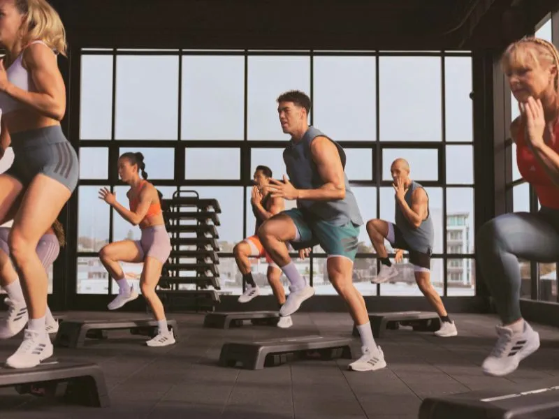 Group fitness class with six people performing step exercises on SMARTSTEP equipment.